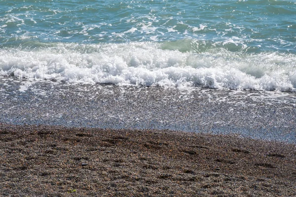 Морская вода с пеной на галечном пляже . — стоковое фото