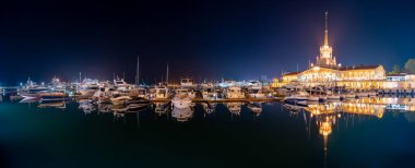 Deniz İstasyonu, su yansıması ile gece ışık ile aydınlatılmış Soçi. Yat ve tekne iskelede.