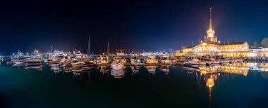 Deniz İstasyonu, su yansıması ile gece ışık ile aydınlatılmış Soçi. Yat ve tekne iskelede.
