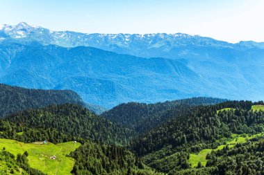 Yeşil dağ sırtları, yüksek dağlarla çevrili. Ufukta karla kaplı dağ zirveleri. Krasnaya Polyana, Sochi,, Rusya Federasyonu.