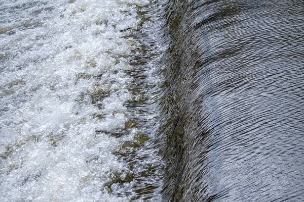 A small flat cascade in a calm river. Water background
