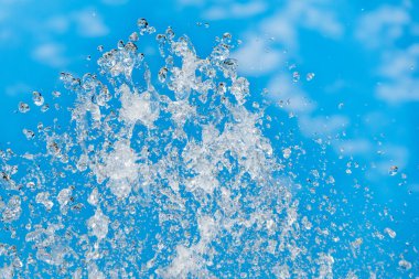 Mavi gökyüzü arkaplanına su sıçrıyor. Çeşme, mavi gökyüzüne karşı bir su jeti.