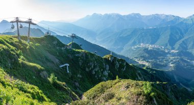 Yazın Aibga Dağları 'nın tepesinden kayak merkezi Rosa Khutor' a kadar günbatımının panoramik manzarası. Teleferikle dağlarda güzel bir gün batımı. Krasnaya Polyana, Sochi, Kafkasya, Rusya.