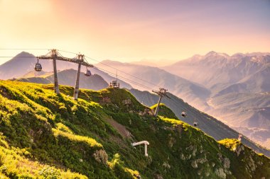 Yaz günbatımında Vew 'den kayak merkezi Rosa Khutor' ya Aibga Dağları 'nın tepesinden. Teleferikli dağlarda güzel pembe ve turuncu gün batımı. Krasnaya Polyana, Sochi, Kafkasya, Rusya