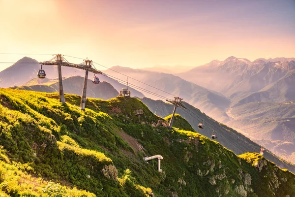 Yaz günbatımında Vew 'den kayak merkezi Rosa Khutor' ya Aibga Dağları 'nın tepesinden. Teleferikli dağlarda güzel pembe ve turuncu gün batımı. Krasnaya Polyana, Sochi, Kafkasya, Rusya