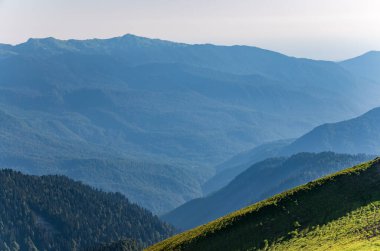 Yeşil dağ yamacı. Gün batımında sisli dağların katmanları. Çok katmanlı sisli isimler. Krasnaya Polyana, Sochi, Rusya.
