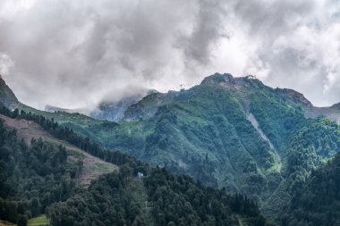 Bulutlu yaz gününde teleferikli yeşil dağ yamacı. Krasnaya Polyana, Sochi, Kafkasya, Rusya. Tatil ve tatiller dağlarda.