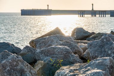 Limanın arka planında büyük taşlar ve kayalar var. Deniz kıyısındaki büyük taşların dalgalanması.