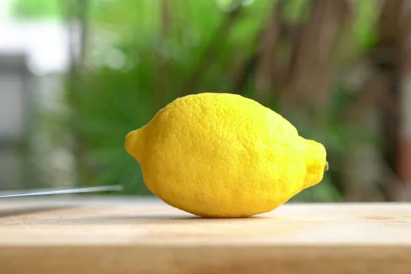 Un citron sur une planche à découper avec fond de jardin — Photo