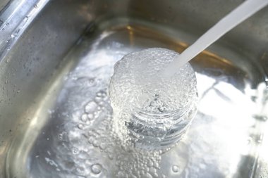 Musluktan plastik konteynıra su ve lavaboya taşar..