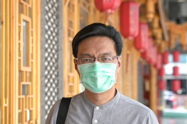 Portrait of Asian Chinese man wearing surgical face mask. clipart