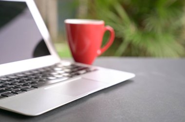 Kırmızı bardakta yeşil arka planı olan bir bilgisayar bilgisayarı. Uzaktan ya da evden çalış. Seçili odak. Boşluğu kopyala.