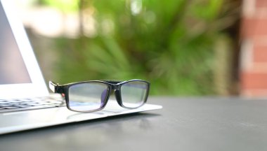 Ev ve yeşil doğa geçmişi olan dizüstü bilgisayarda gözlük. Uzayı kopyala Uzaktan veya ev konseptinden çalış.