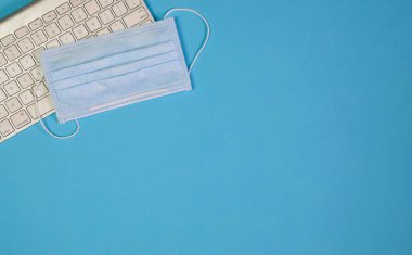 Tıbbi yüz maskesi klavyenin üstünde. Üst Manzara. Boşluğu kopyala.