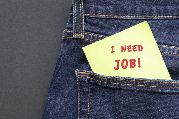 ジーンズのポケットから出てきた黄色い紙に赤い言葉で仕事が必要です 雇用の概念 — ストック写真