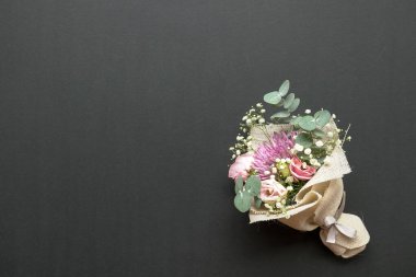 El çiçeği buketi kasımpatı, güller ve yeşil yapraklardan oluşur. Siyah arka planda. Boşluğu kopyala.