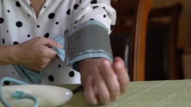 Kadın kendi kan basıncını dijital tansiyon cihazıyla ölçüyor..