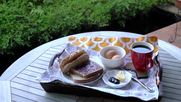 早餐的景色包括咖啡 黄油和放在桌上盘子里的鸡蛋 健康的生活理念 花园背景 — 图库视频影像