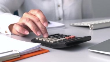 Hesap makinesini kullanan muhasebeci ya da iş kadını. Hesap makinesinin tuşlarına basan parmaklarının yakın görüntüsü.