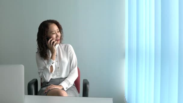 亚洲的中国女商人在电话里交谈和争论 坐在她的办公室窗户旁边 — 图库视频影像
