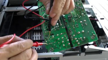 Elektrikçi bozuk bir ses cihazını tamir ediyor. Elektrik akımı baskı devresi üzerinde test ediliyor, pcb çoklu metre ile