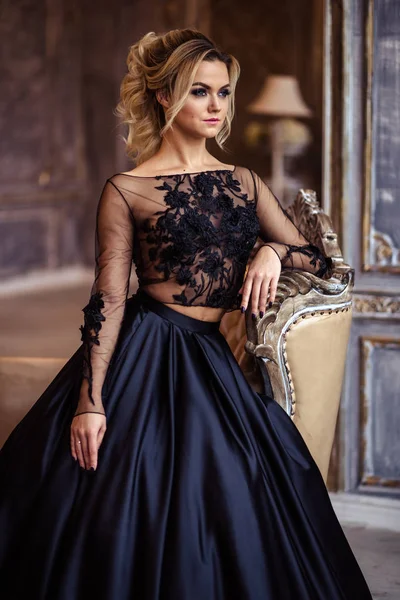 Hermosa mujer joven en vestido de noche negro magnífico con maquillaje perfecto y estilo de pelo —  Fotos de Stock