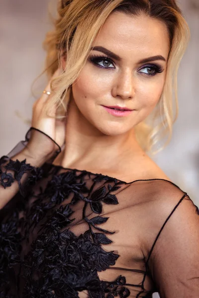 Hermosa mujer joven en vestido de noche negro magnífico con maquillaje perfecto y estilo de pelo —  Fotos de Stock