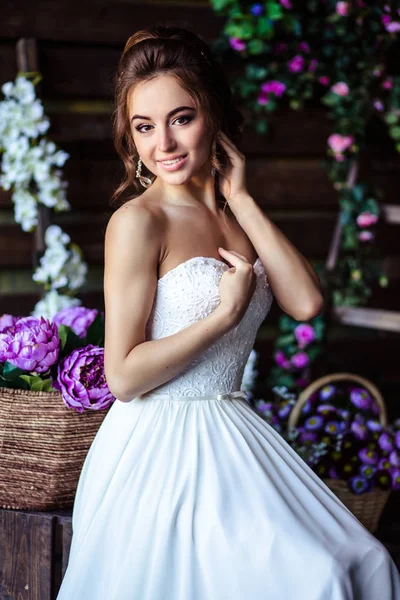 Preciosa novia mujer joven en un vestido de novia con maquillaje perfecto y peinado — Foto de Stock