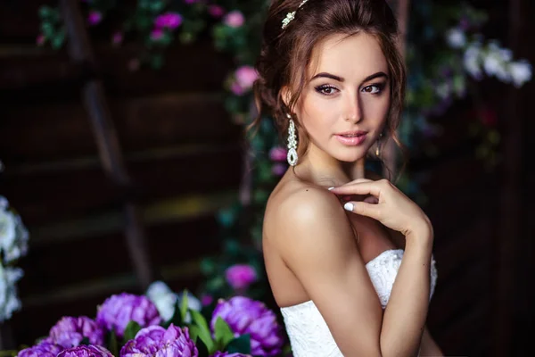 Preciosa novia mujer joven en un vestido de novia con maquillaje perfecto y peinado — Foto de Stock