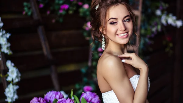 Preciosa novia mujer joven en un vestido de novia con maquillaje perfecto y peinado — Foto de Stock