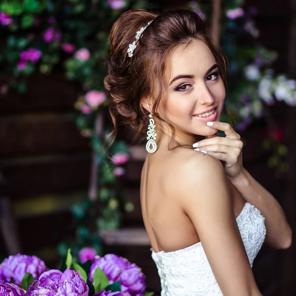 Preciosa novia mujer joven en un vestido de novia con maquillaje perfecto y peinado — Foto de Stock