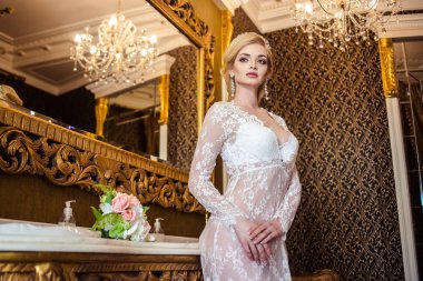 Beyaz bir banyo iç çamaşırlarıyla güzel sarışın genç kadın. Gelinin sabah