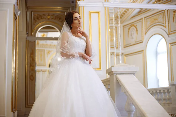 Krásná mladá žena nevěsta v luxusních svatebních šatech v interiéru — Stock fotografie