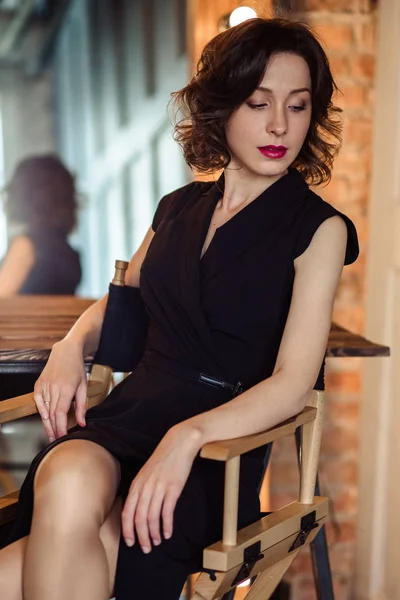 Mujer joven tierna en un vestido negro con maquillaje natural y peinado —  Fotos de Stock