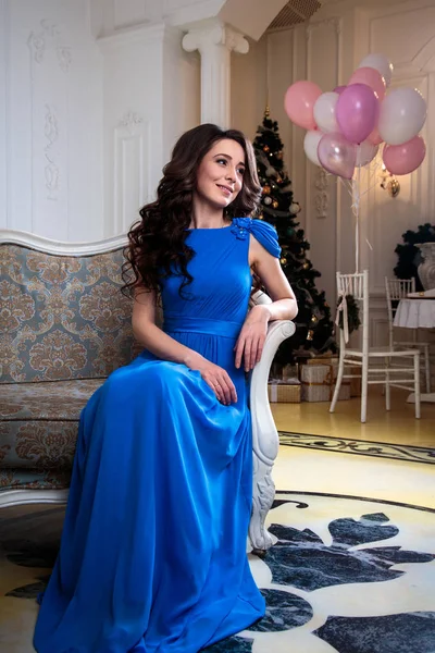 Hermosa mujer joven en un vestido de noche azul con globos de aire sobre fondo de Navidad —  Fotos de Stock