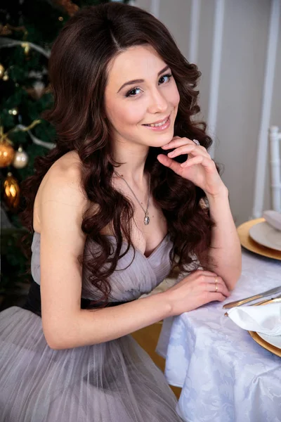 Schöne junge Frau in luxuriösem Abendkleid mit Luftballons vor weihnachtlichem Hintergrund — Stockfoto