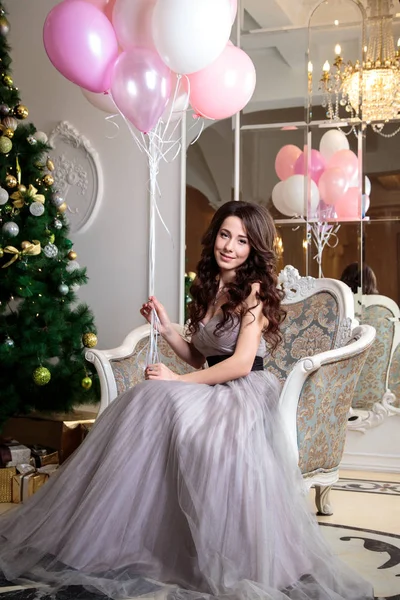 Hermosa mujer joven en vestido de noche de lujo con globos de aire sobre fondo de Navidad —  Fotos de Stock