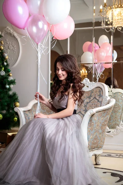 Belle jeune femme en robe de soirée de luxe avec des ballons à air sur fond de Noël — Photo