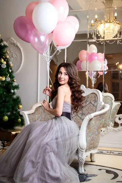 Bela jovem mulher em vestido de noite de luxo com balões de ar sobre fundo de Natal — Fotografia de Stock