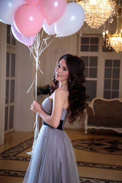 Bela jovem mulher em vestido de noite de luxo com balões de ar no interior — Fotografia de Stock