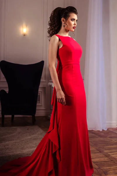 Jeune femme dans une magnifique robe de soirée rouge à l'intérieur — Photo