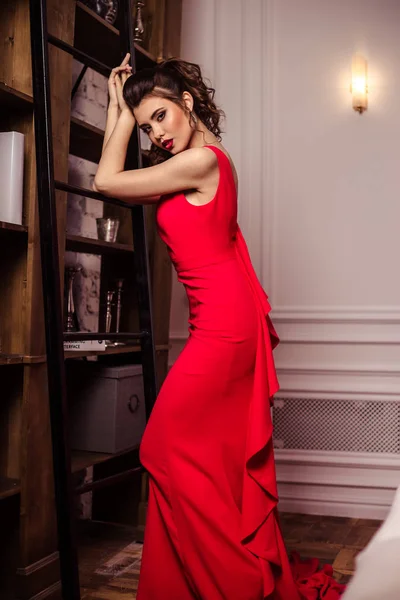 Jeune femme dans une magnifique robe de soirée rouge à l'intérieur — Photo