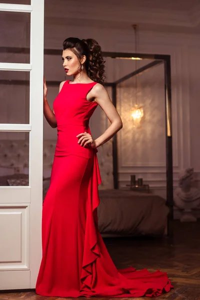 Jeune femme dans une magnifique robe de soirée rouge à l'intérieur — Photo