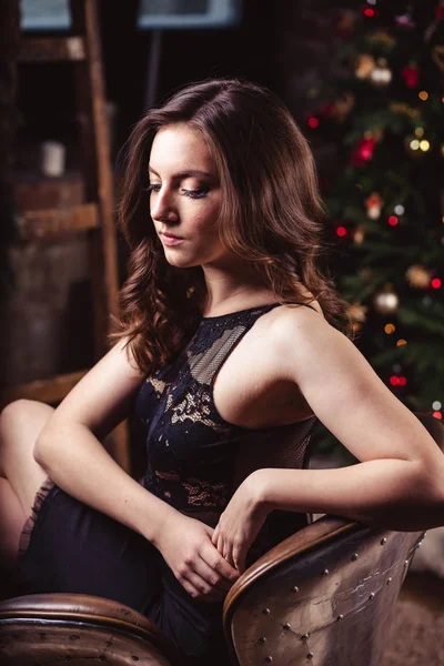 Noel arka plan üzerinde siyah elbiseli genç esmer kadın portresi — Stok fotoğraf