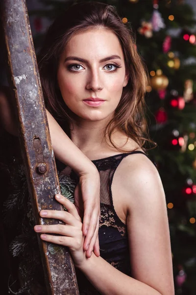 Ritratto di giovane donna bruna in abito nero su sfondo natalizio — Foto Stock