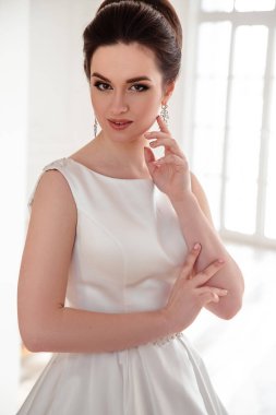 zarif saç ve makyaj uzun lüks gelinlik giyen güzel esmer gelin portresi