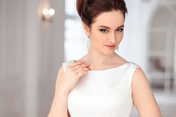Close-up portrait of beautiful brunette bride with elegant hairstyle and makeup wearing long luxury wedding dress — Stock Photo, Image