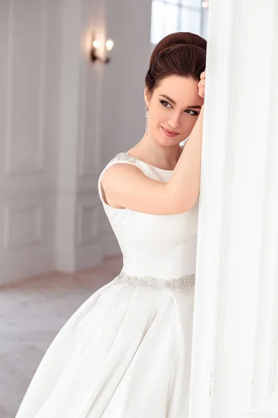 Retrato de bela noiva morena com penteado elegante e maquiagem vestindo vestido de noiva de luxo longo — Fotografia de Stock