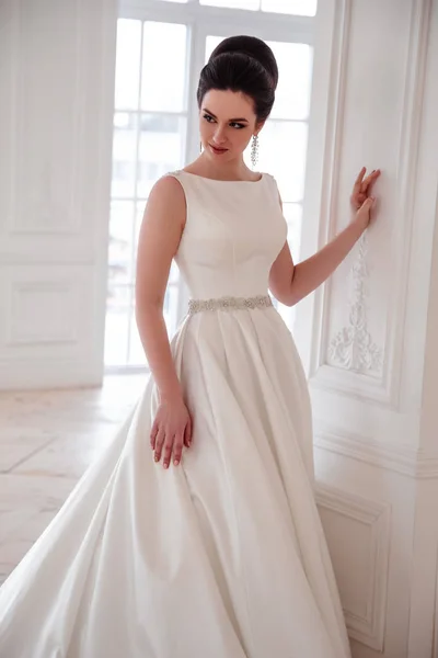 Ritratto di bella sposa bruna con acconciatura elegante e trucco indossando lungo abito da sposa di lusso — Foto Stock