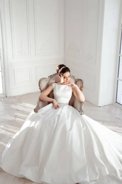 Retrato de bela noiva morena com penteado elegante e maquiagem vestindo vestido de noiva de luxo longo — Fotografia de Stock